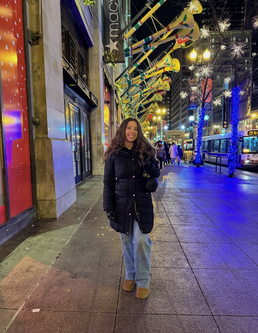 Analise McCord smiling on a city sidewalk decorated with holiday lights